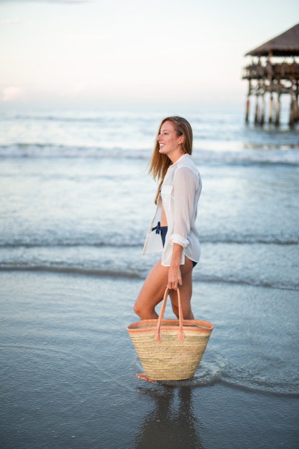 What to Pack in a Beach Bag: 20 Beach Essentials, Wearing Navy High Waisted Swimsuit, White Linen Shirt and Woven Straw Beach Bag | Sunshine Style