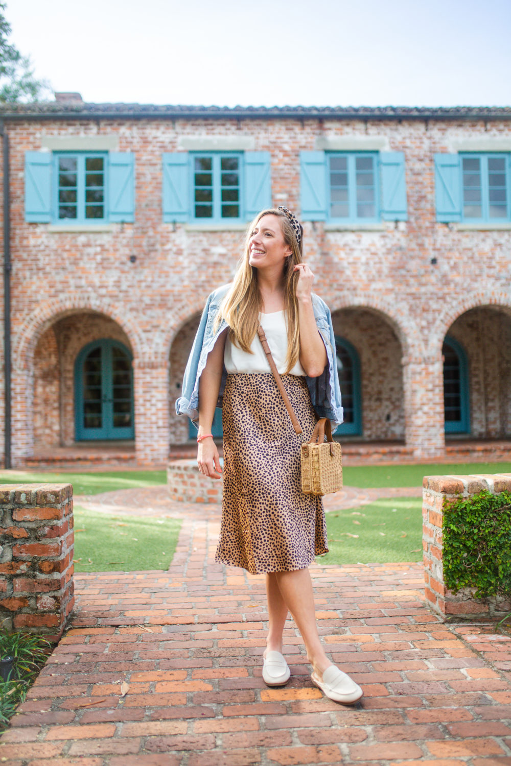 woman sharing how to style a leopard skirt with white top and denim jacket