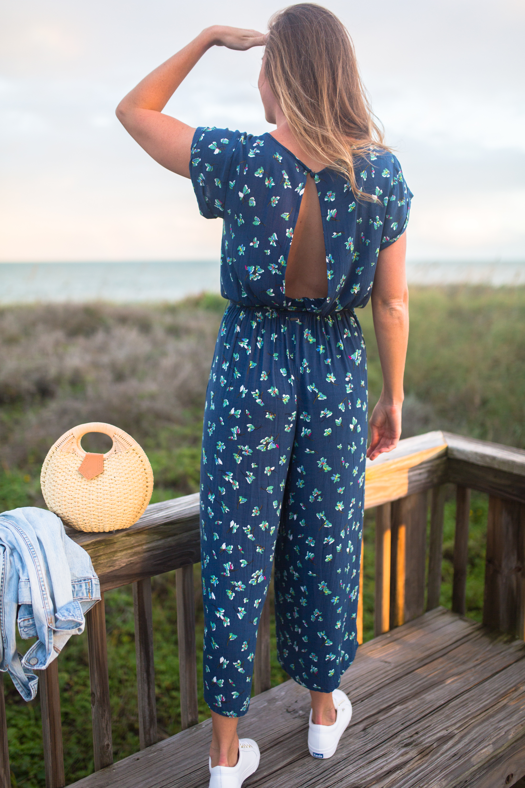 woman in a Tropical Winter Getaway wearing Blue Floral Jumpsuit with open back details 