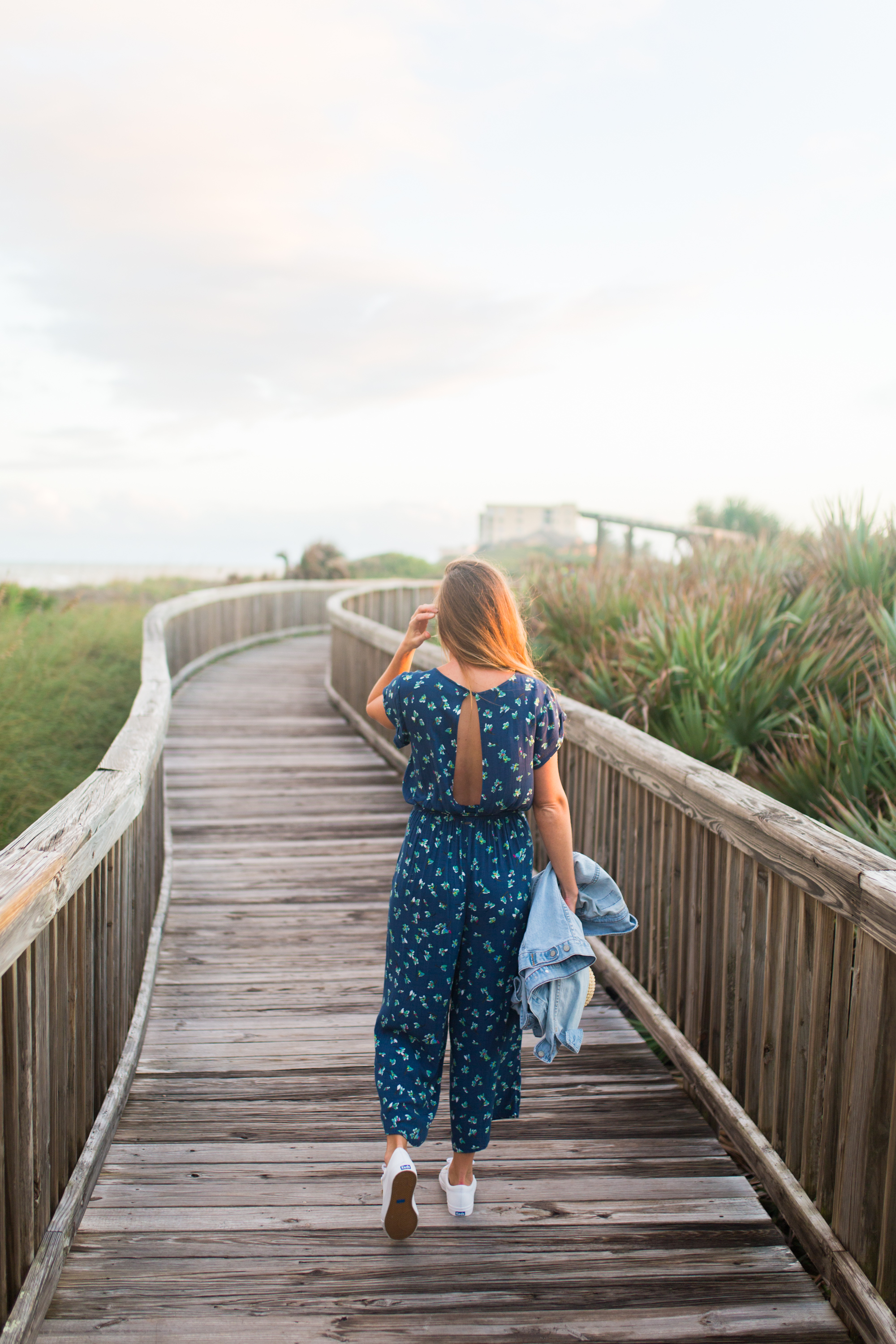 woman in a Tropical Winter Getaway wearing Blue Floral Jumpsuit walking in a pathway