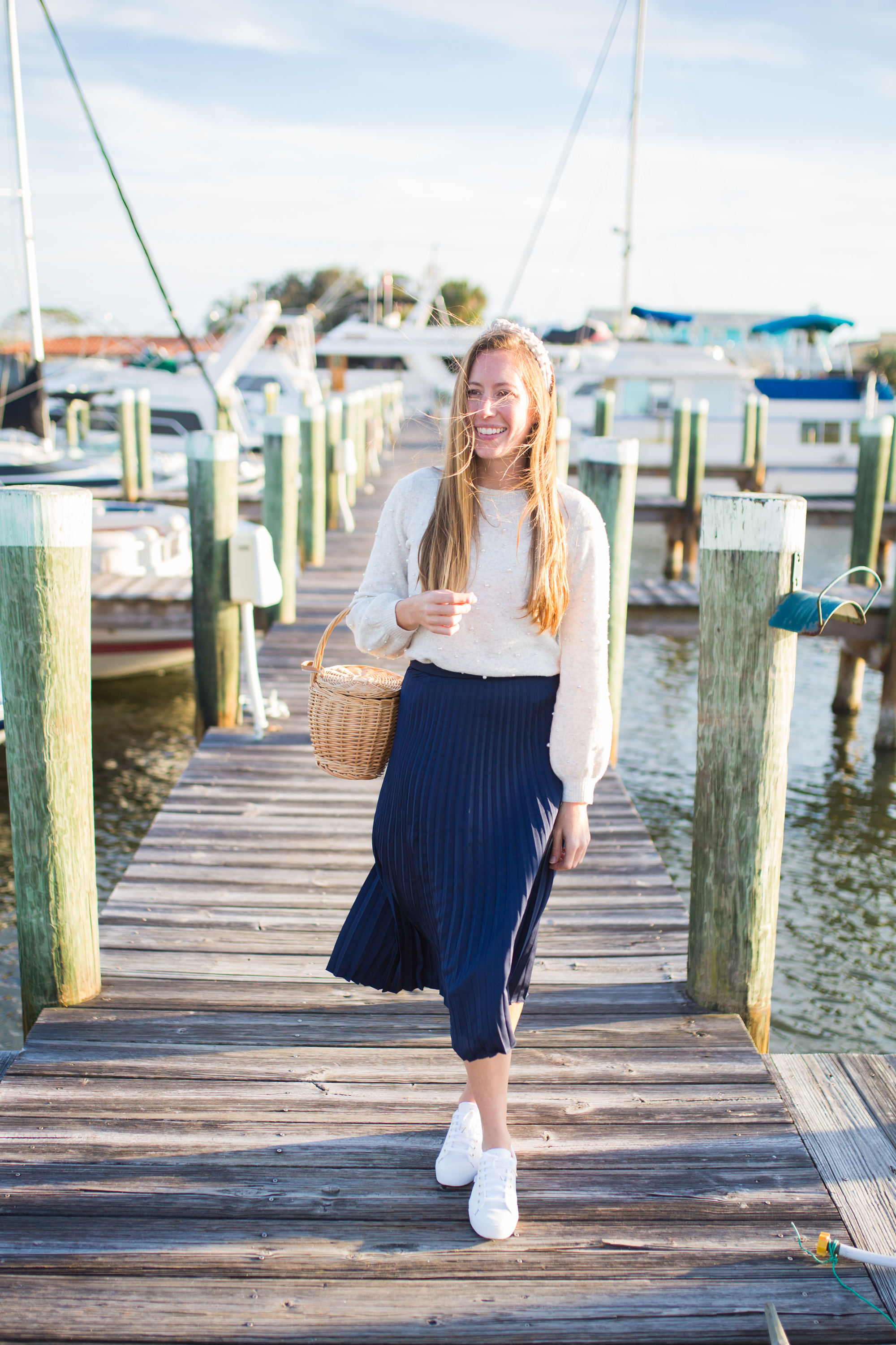 Woman in the dock and wearing electric pleated skirt and sweater 