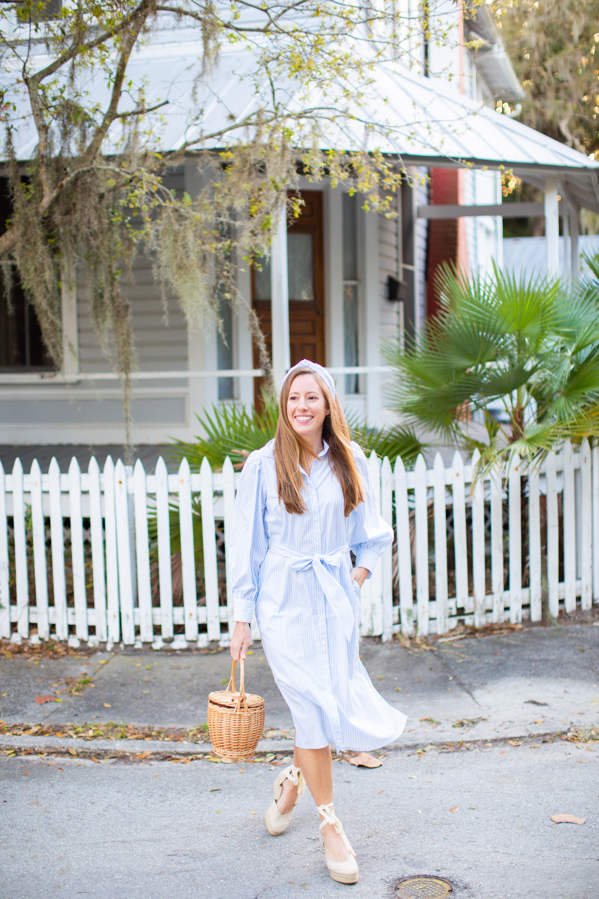 woman walking outside and wearing a Striped Spring Dress, headband, and carrying a bag