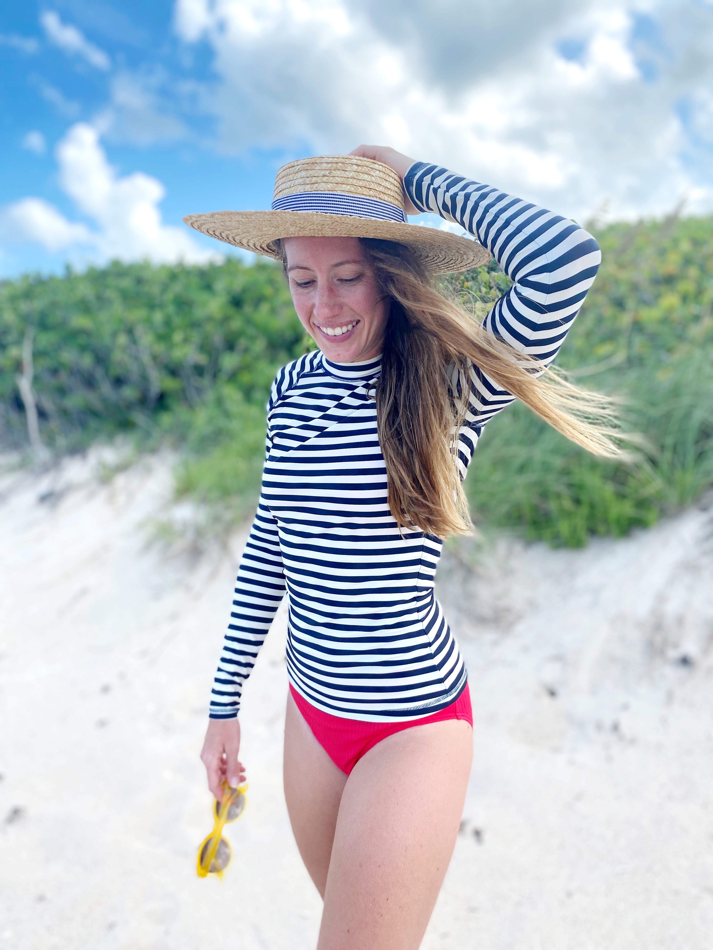 woman walking at the beach and wearing rash guard 