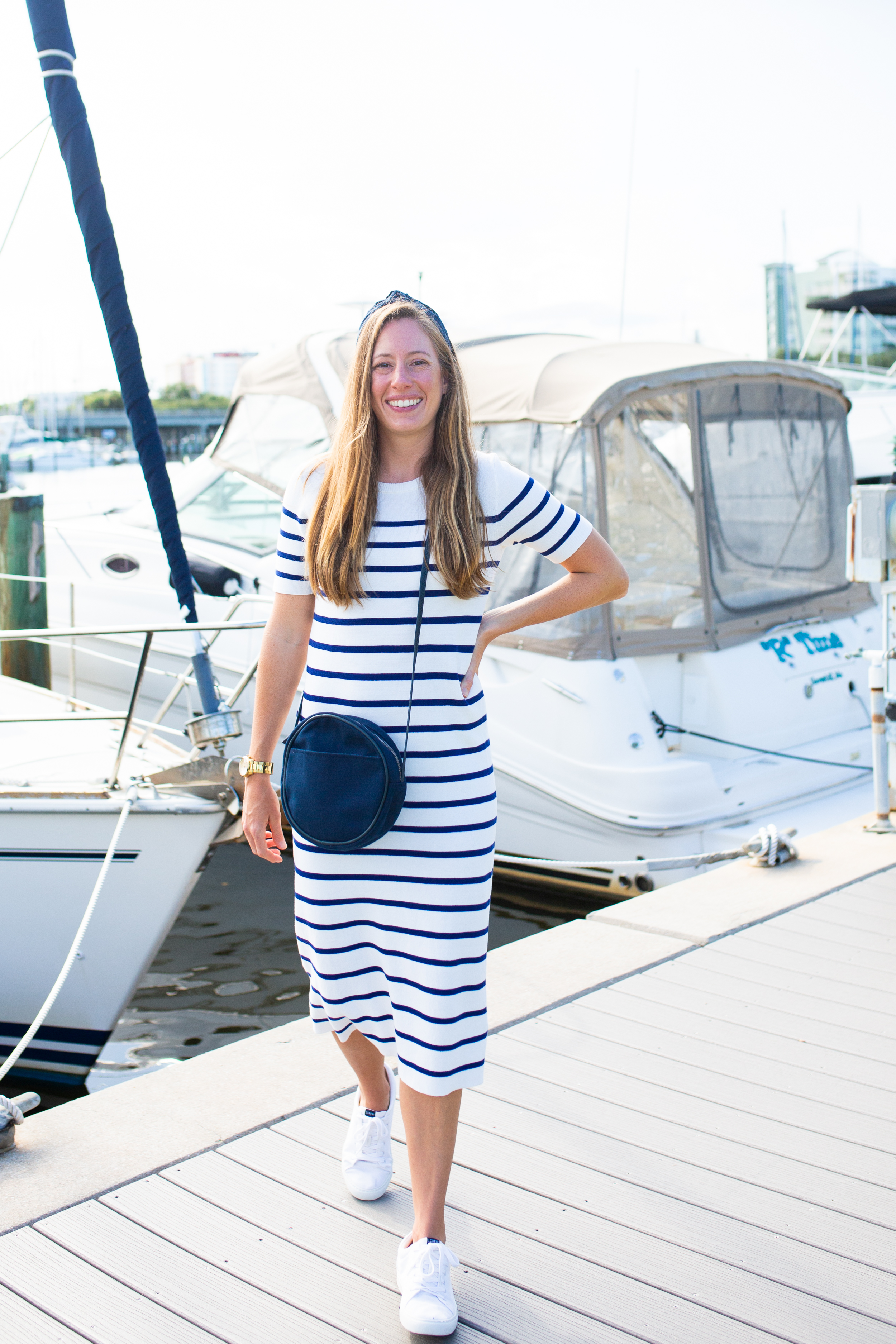 woman at the marina wearing a striped dress and denim bag