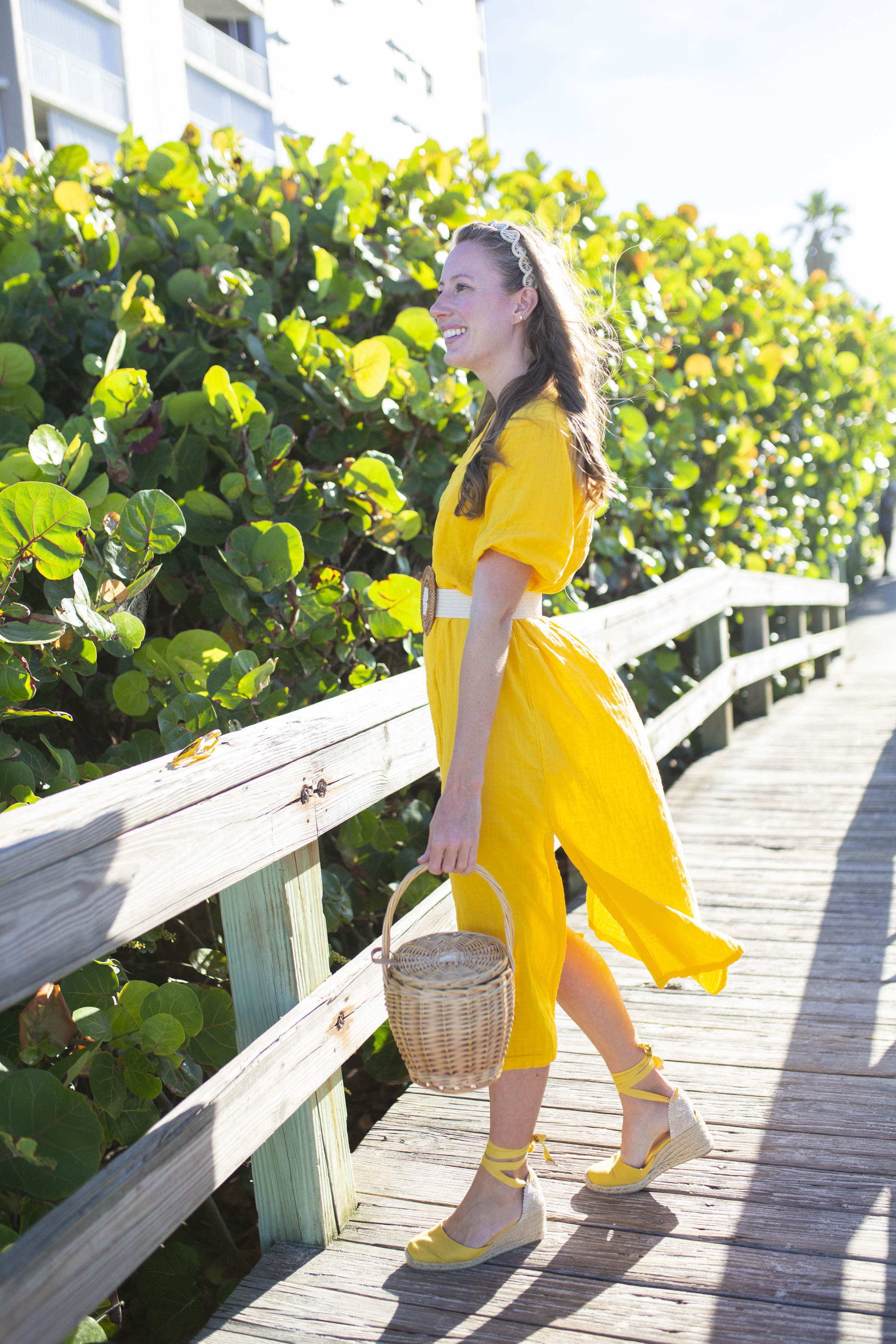 girl wears woven palm headband  with yellow caftan, espadrille wedges and basket bag at the beach